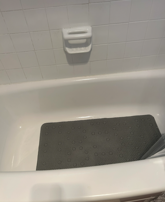 Clean white bathtub with a non-slip mat after a deep clean