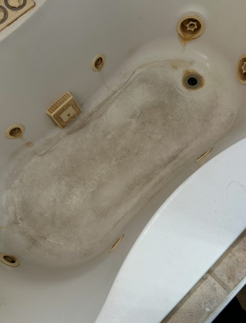 Jetted tub with heavy soap scum and residue before cleaning