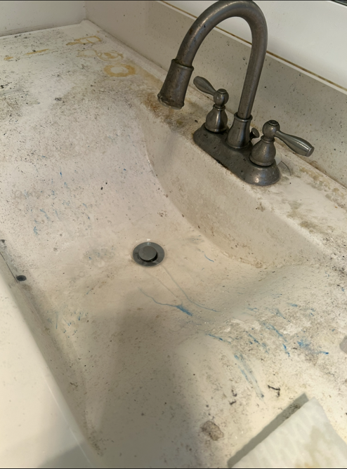Bathroom vanity sink heavily soiled with paint and grime before cleaning